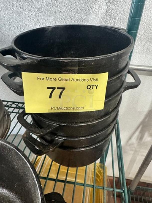 Stacked cast iron small Dutch ovens without lids, marked BIDX6, showing a black finish and sturdy side handles in used condition.