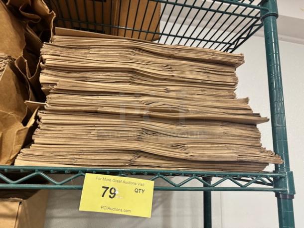 Stack of Duro 1/6 paper sack bags on shelf, unused, natural brown color, auction tag showing quantity 79.