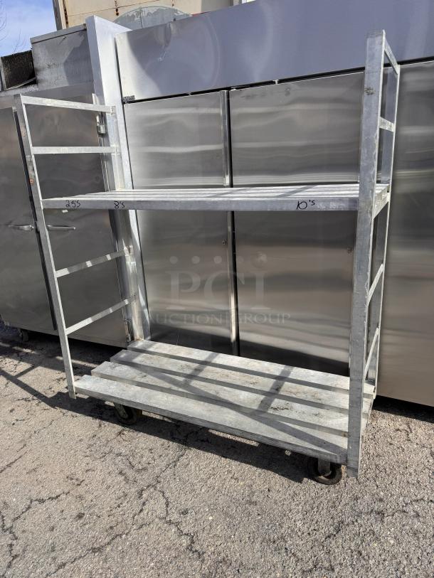 Metal mobile rack with two shelves, caster wheels, and visible wear. Markings include measurements "25.5" and "10".
