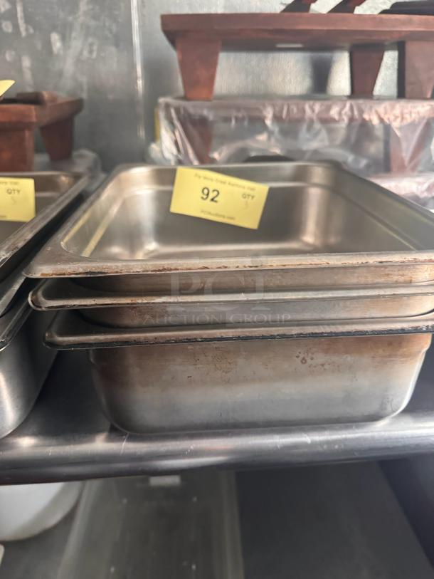 Stainless steel food pan, model BIDX3, stacked on a shelf. Visible label: "92." Used condition with some wear.