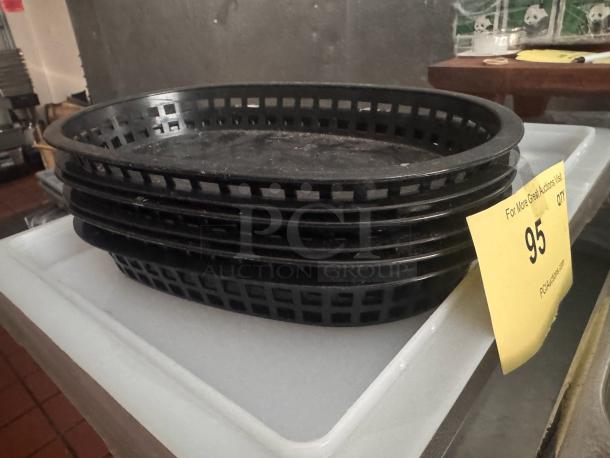 Lot of 6 black food baskets in used condition, stacked on a white surface. Auction tag showing lot number 95.