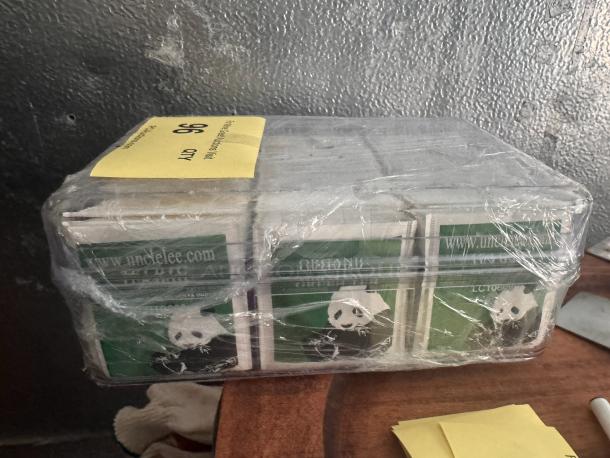 Pack of Uncle Lee green tea bags wrapped in plastic, featuring panda design, visible website URL, and labeled for auction.