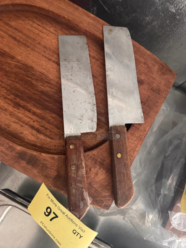 Lot of 2 vintage knives with wooden handles and steel blades, showing signs of wear, on a wooden surface.