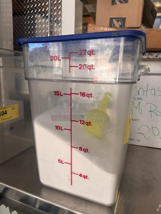 22 Quart clear square food storage container with blue lid, volume markings in quarts and liters, visible yellow scoop inside.