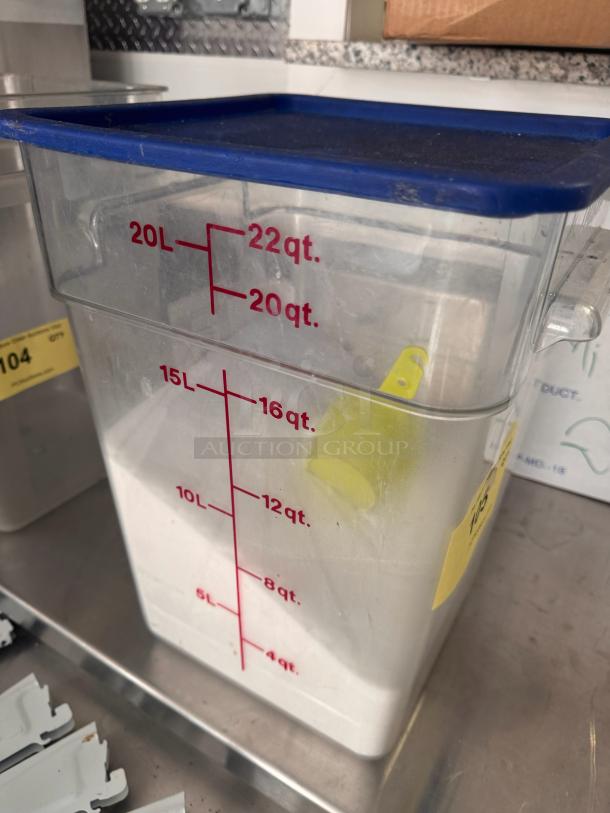 22 quart clear square food storage container with blue lid, marked with red measurements in quarts and liters.