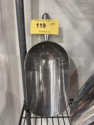 Metal ice scoop with a curved handle, shiny finish, displayed on a wire shelf. Auction tag indicates item 119.