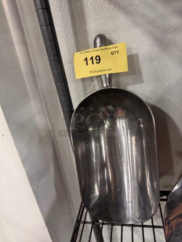 Stainless steel ice scoop with a contoured handle, moderate wear, marked with auction tag "119 QTY" from PCIAuctions.com.