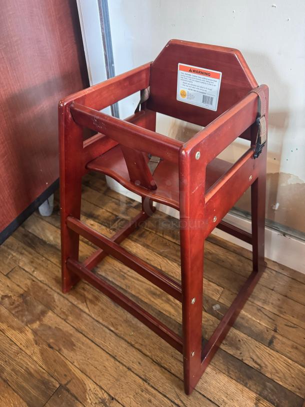 Wood high chair with rich finish, harness strap, and warning label. Sturdy construction, excellent condition, suitable for toddlers.