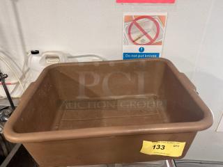 Brown plastic bus tub with handles, showing signs of use. Auction tag 133 from PCAuctions.com attached.