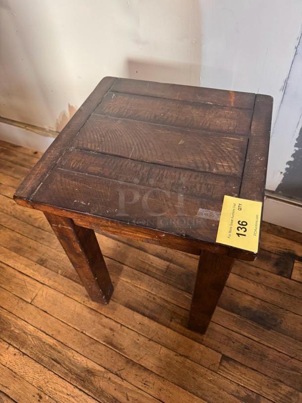 Rustic wooden side table with a paneled top, showing wear and patina. Auction tag labeled "136" is visible on the edge.