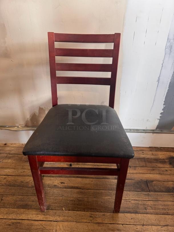 Wooden dining chair BIDX3 with ladder back design and black upholstered seat. Some visible wear on legs, overall sturdy condition.