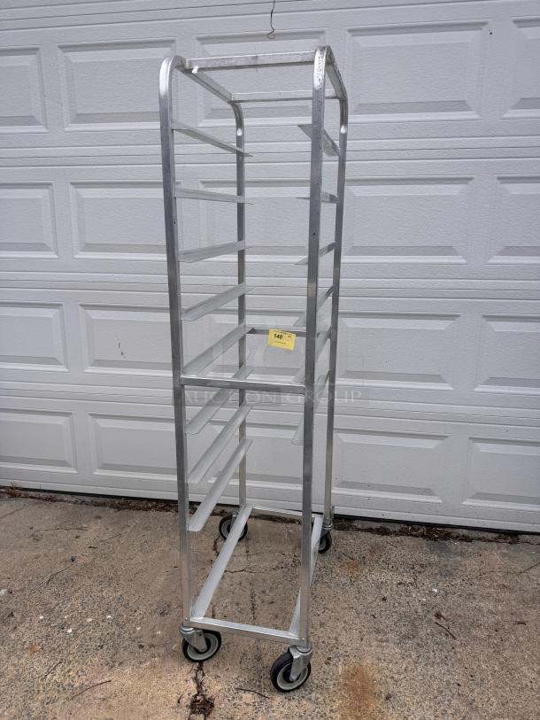 Aluminum cooling rack with multiple shelves, caster wheels, and a label marked "140" for auction. Good condition.