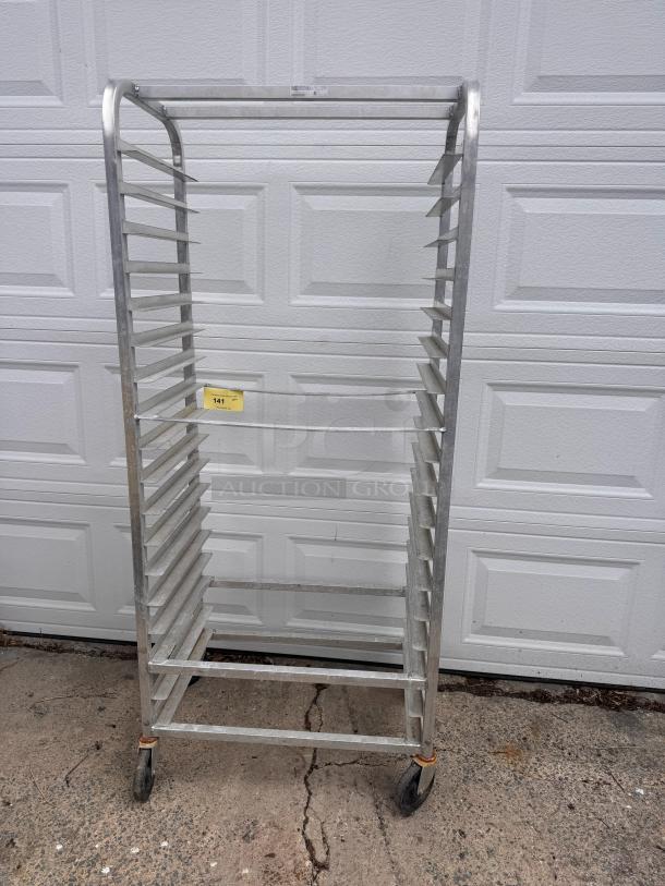 Aluminum cooling rack with multiple shelves, on wheels. Appears in fair condition. Yellow tag labeled 141 is visible.