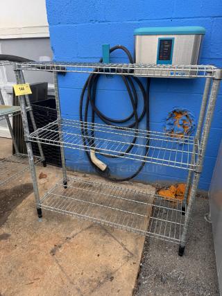 Metallic 36" wire shelf, three tiers, sturdy build, outdoor setting, industrial style, minor wear. Auction tag visible.