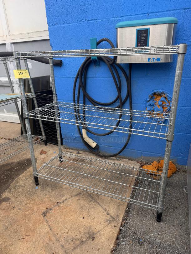 Metal wire shelf, 36 inches, three tiers, in used condition. Sturdy design with visible wear. Tag marked "144."