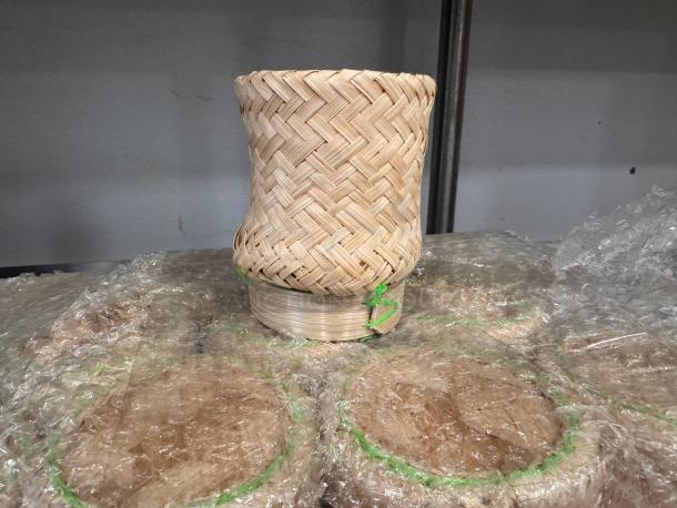 Bamboo basket with intricate woven design, excellent condition, stacked on wrapped packages, labeled "ALL ONE MONEY."