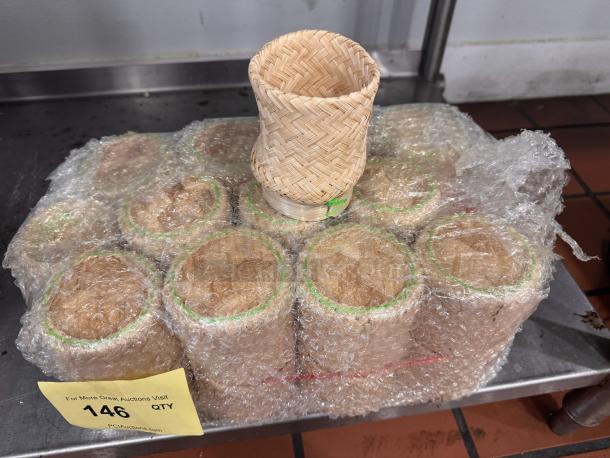 Bamboo basket set wrapped in bubble wrap, showcasing intricate weaving. Auction tag reads "146 QTY" from PCAAuctions.com.