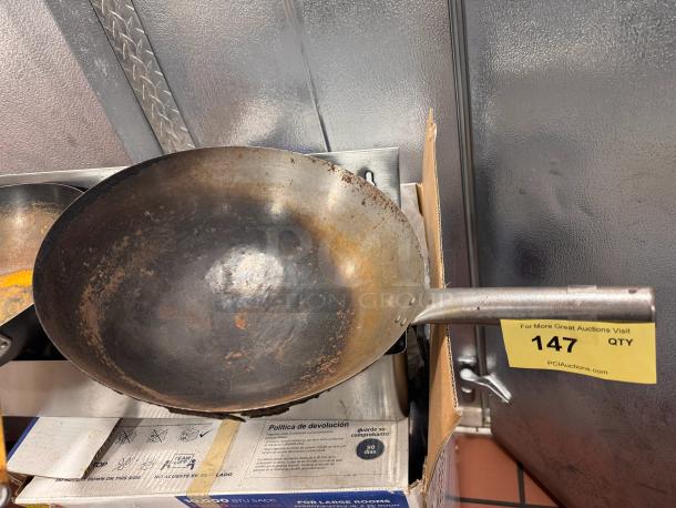 Steel fry pan/wok with a long handle, showing signs of wear. Auction label indicates item 147 from PCI Auctions.