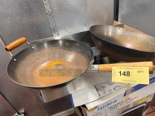 Steel wok with wooden handle, showing signs of rust. Includes auction tag labeled "148" on the handle.