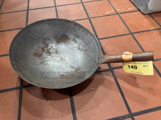 Rustic metal wok with wooden handle, showing wear. Attached auction label with number 149, indicating item for auction.