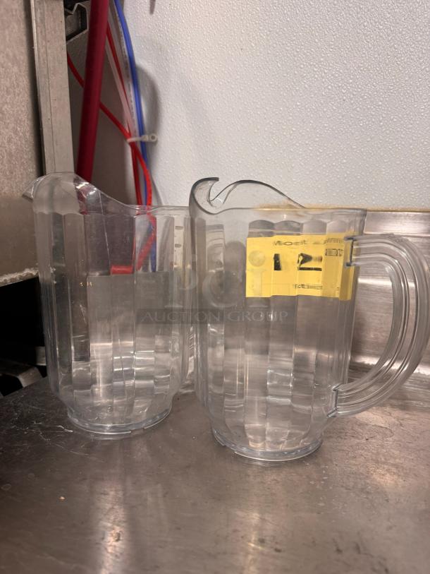 Clear plastic pitcher with handle, fluted design, and pouring spout. Slightly used condition. Yellow label with text "12".