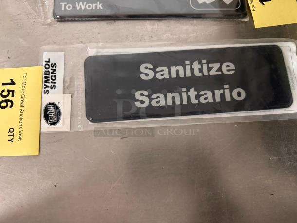 Brand new "Sanitize/Sanitario" sign by Symbol Signs, black with white text, in original packaging.