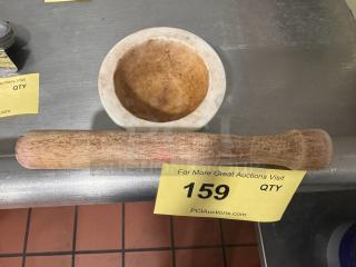 A marble mortar and wooden pestle on a metal surface. Item label indicates auction number 159. Slight wear visible.