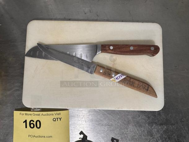 Cutting board with two bar knives featuring wooden handles. One knife marked with "KIWI" sticker. Used condition.