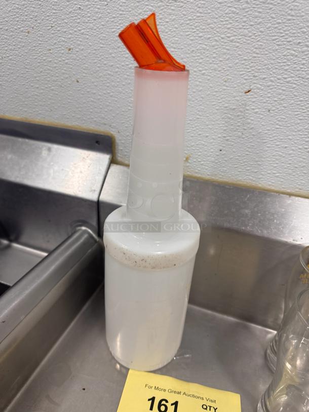 White bar store-and-pour bottle with orange spout, visible minor dirt on top. Ideal for efficient drink preparation.