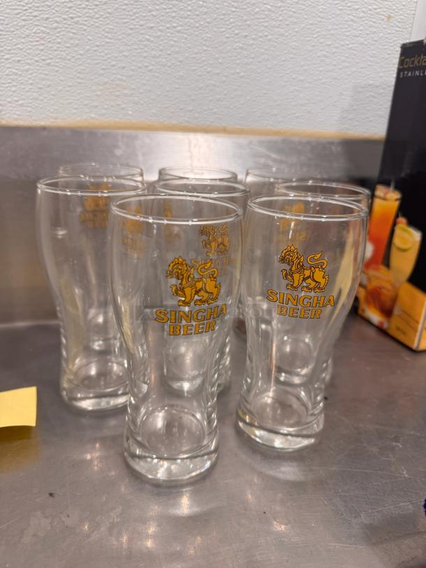 Set of 8 Singha Beer glasses, clear with gold logo, excellent condition, ideal for collectors or beer enthusiasts.