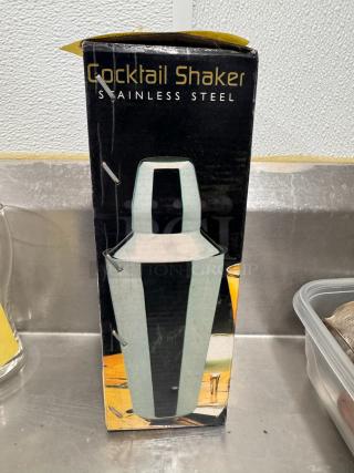 Stainless steel cocktail shaker with original packaging. Box shows some wear. Measures approximately 10 inches tall.