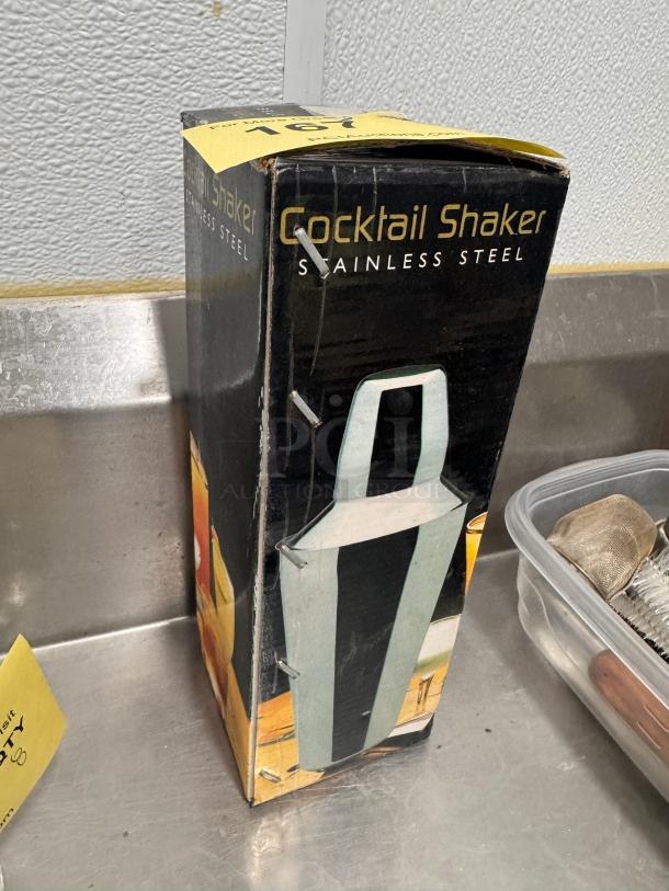 Stainless steel cocktail shaker in original box. Box shows signs of wear with visible scuffs. Ideal for home bar setups.