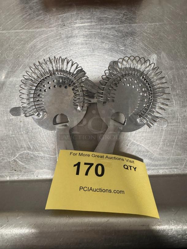 Two metal bar strainers with coiled springs on a stainless steel surface, labeled "170" at PCI Auctions.