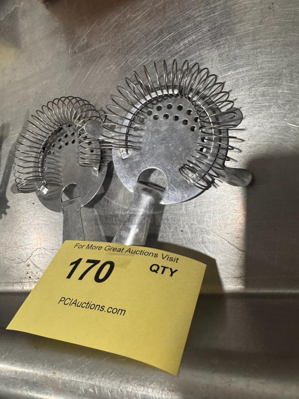 Stainless steel bar strainer with spring coil, perforated design. Auction tag marked "170, PCI Auctions.com."