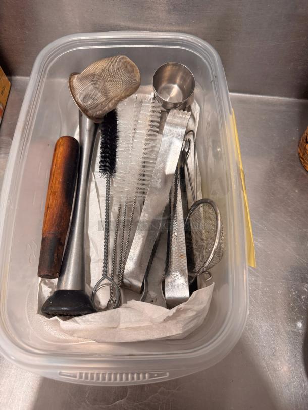 Plastic container with assorted bar tools: muddler, mesh strainer, jigger, cocktail strainer, and brush. Good condition.
