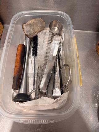 Plastic container with assorted bar tools: muddler, mesh strainer, jigger, cocktail strainer, and brush. Good condition.