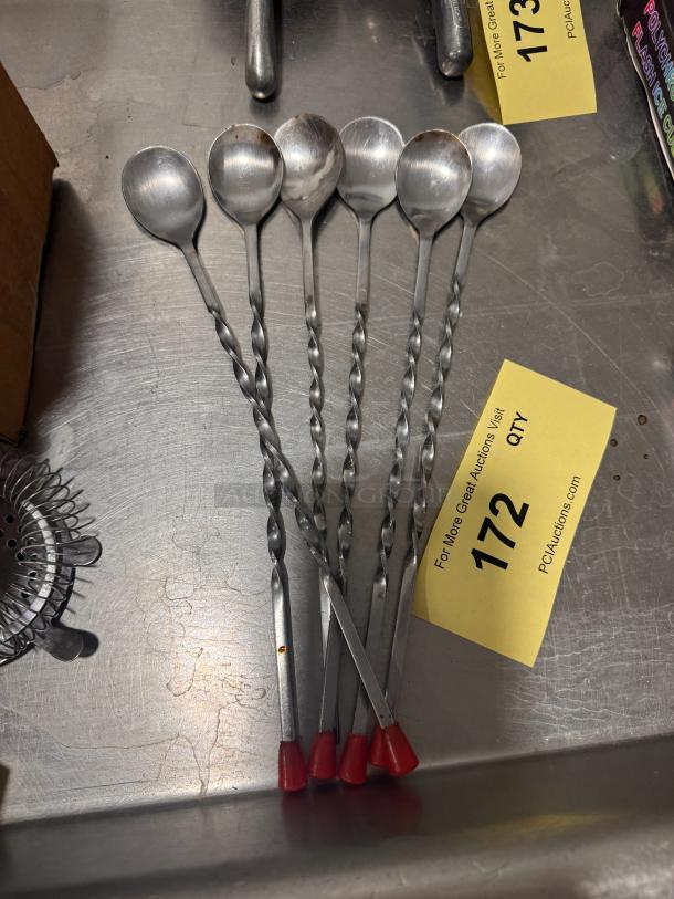 Set of six BIDX6 bar spoons with twisted handles and red tips. Stainless steel, used condition. Auction tag visible.