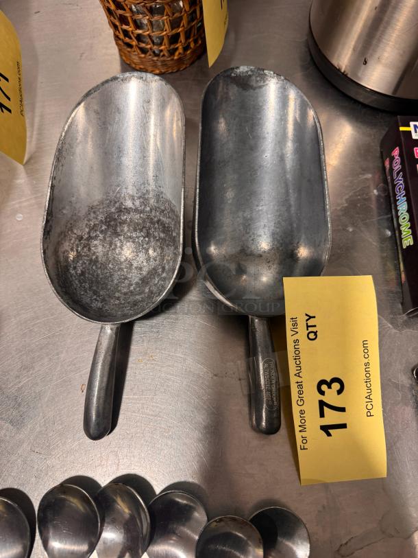 Lot of 2 metal bar scoops, used condition, label on handle, auction tag "173."