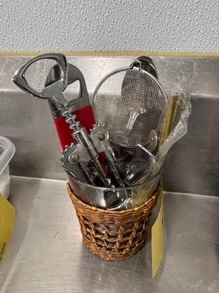 Lot of miscellaneous bar tools in a woven basket, includes corkscrew, strainer, and more. Good condition. All for one price.