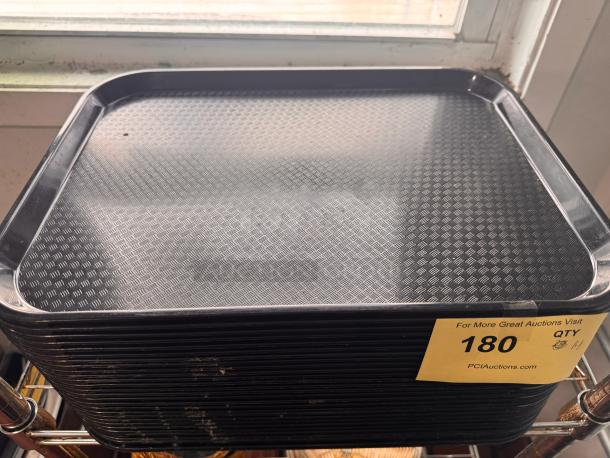 Black plastic tray with textured surface, stack of similar trays, auction tag indicating lot number 180, in used condition.