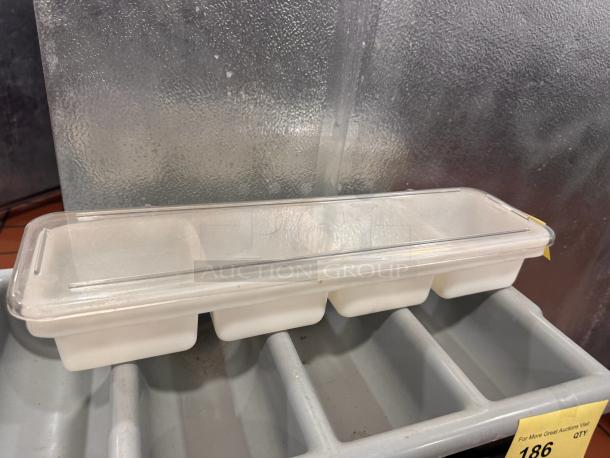 Clear plastic condiment tray with a lid and four compartments. Appears in good condition, shown on a gray rack.