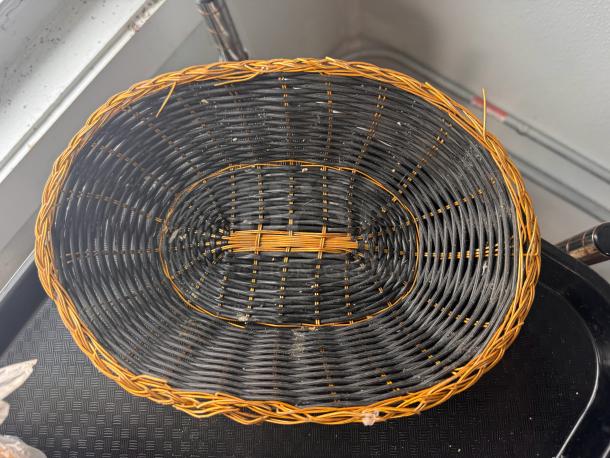 Woven oval food basket BIDX13, featuring a black and tan design. Sturdy construction, in good condition. Perfect for display or storage.