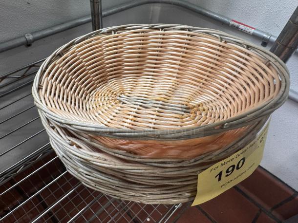 Wicker food basket with oval shape, light brown color, signs of wear, placed on a metal shelf. Auction tag with number 190.