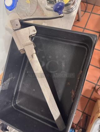 Heavy-duty metal can opener with a blue handle. Appears used, in good working condition. Suitable for commercial use.