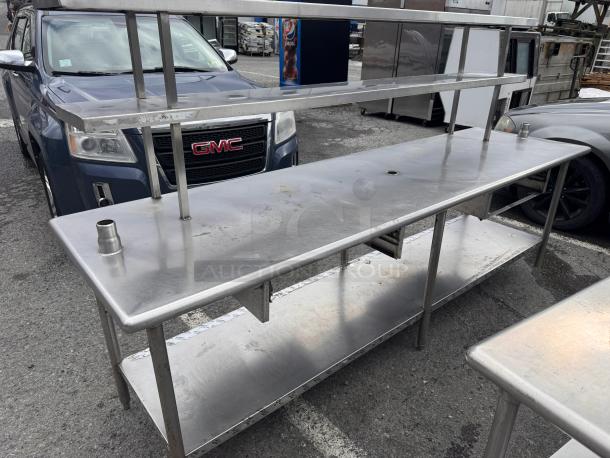 8ft stainless steel work table with overhead shelf, used condition, includes lower shelf for extra storage.