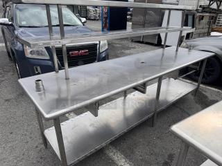 8ft stainless steel work table with overhead shelf, used condition, includes lower shelf for extra storage.