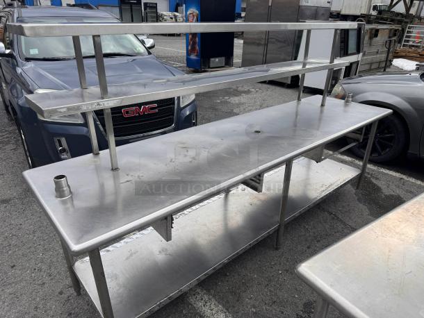 8ft stainless steel work table with overhead shelf, used condition, sturdy construction, open lower shelf, ideal for industrial use.