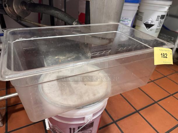 Clear 8in plastic food storage container with measurement markings; light wear visible; auction tag labeled "182."