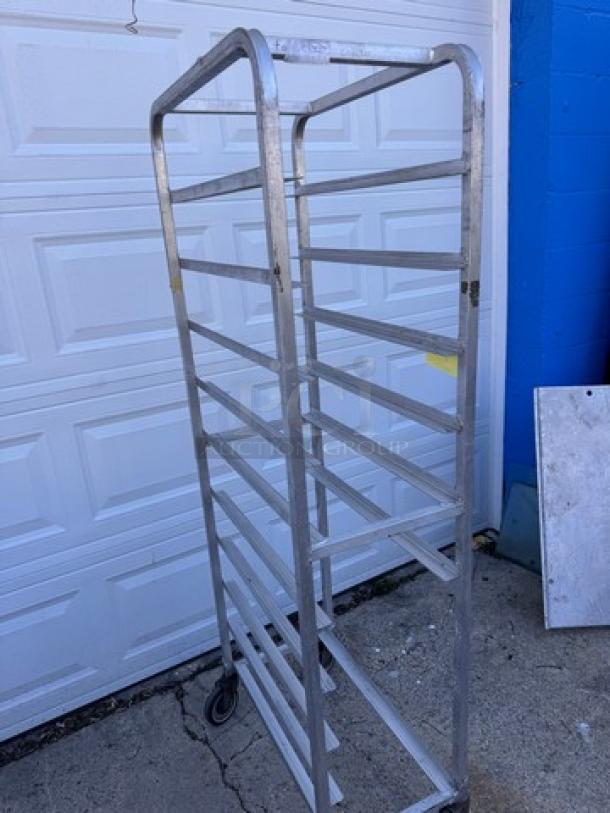 Aluminum pan rack with multiple shelves, two casters, and a sturdy frame. Visible wear suggests used condition.