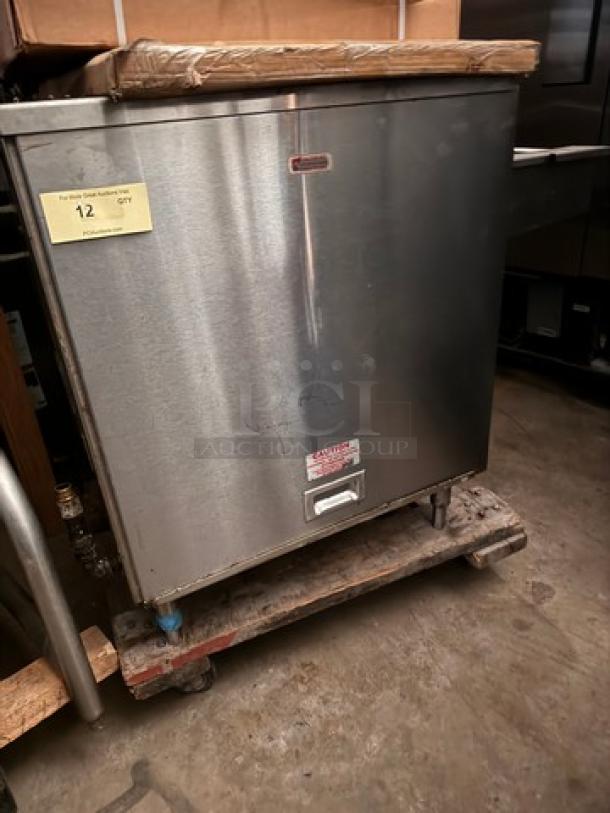 Stainless steel commercial kitchen appliance, Burger IM brand, on a pallet. Features labels with caution and instructions.